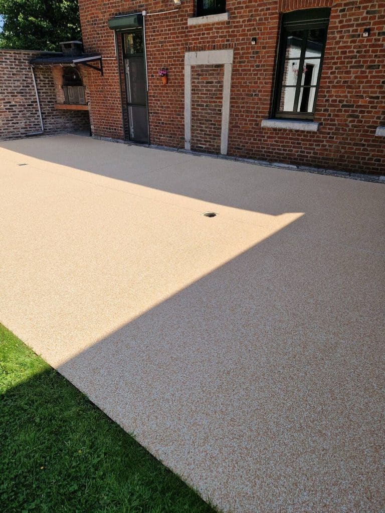 Terrasse en tapis de pierres beige le long d’une maison en brique — Sol Color, Eupen