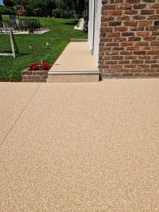 Terrasse en tapis de pierres beige avec marche intégrée, sans joints — Sol Color